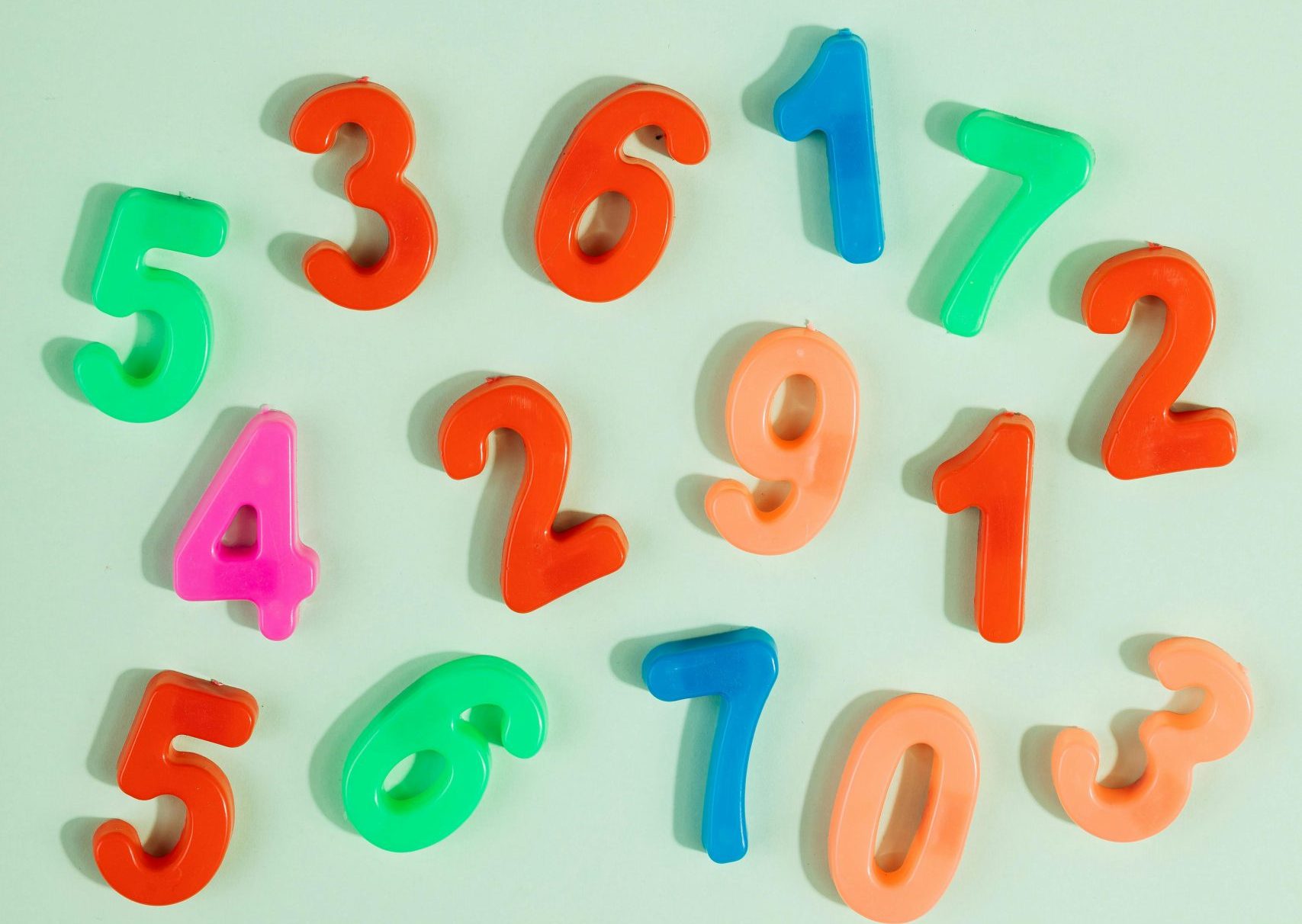 Bright plastic numbers 0-9 on a green background with ample copy space.